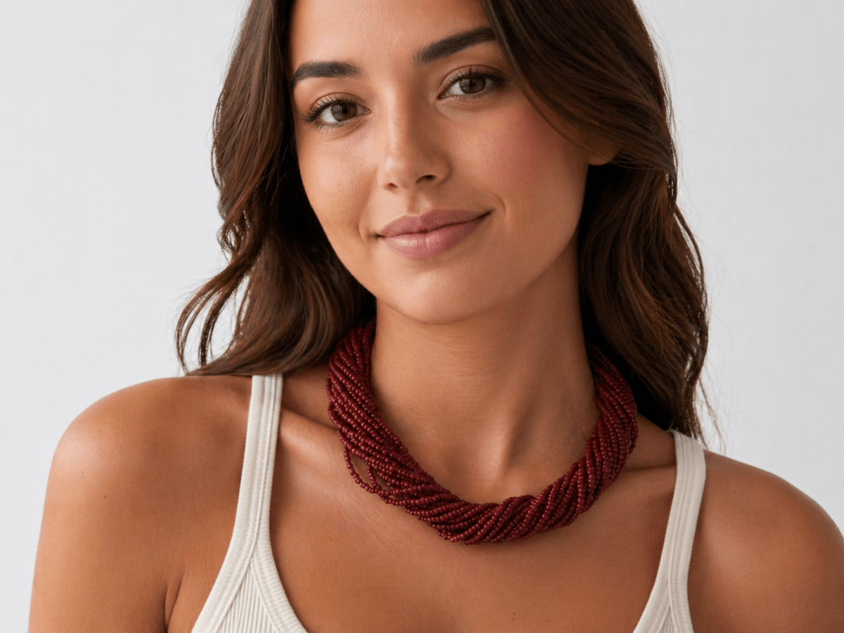 deep red multi strand seed bead necklace being worn by a model  in a white top