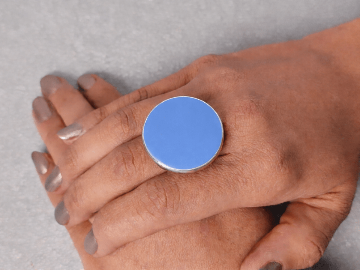 A models hand wearing a round pale blue ring