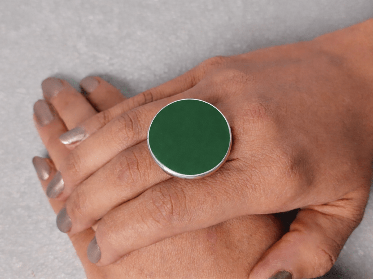 A models hand wearing a round dark green ring