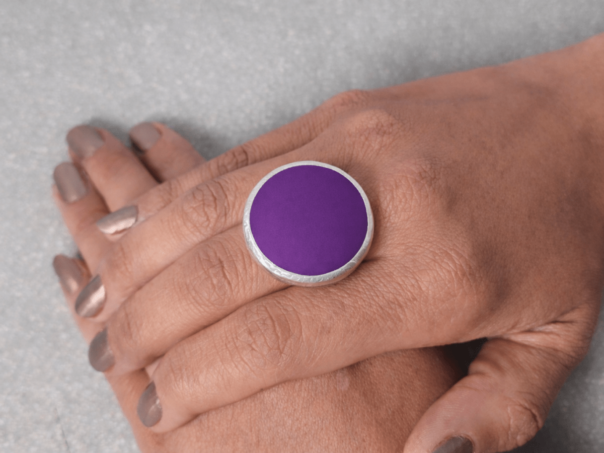 A models hand wearing a round purple ring