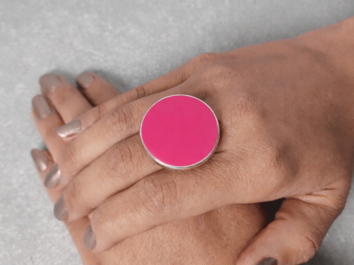 A models hand wearing a round deep pink ring