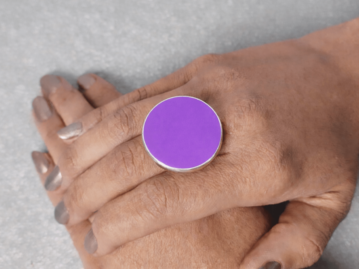 A models hand wearing a round violet ring