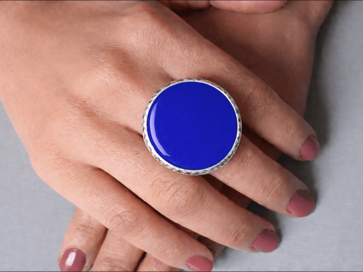 A models hands wearing a large blue ring