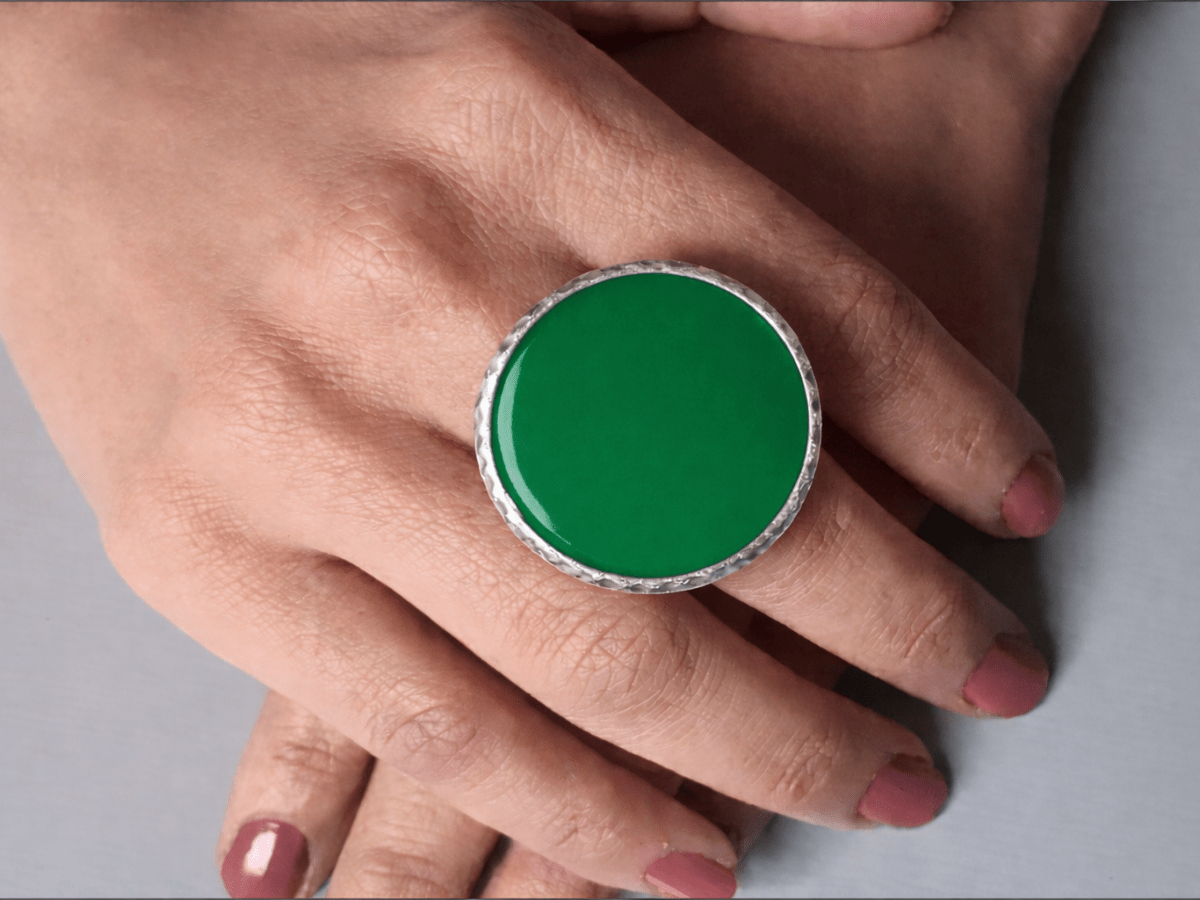 A models hands wearing a large green ring