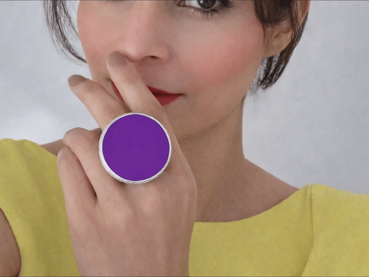 A model wearing a yellow dress and a large purple ring
