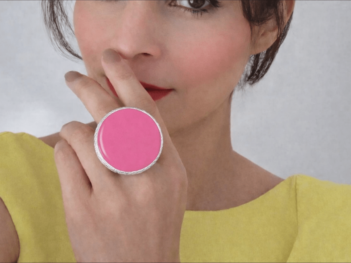 A model wearing a yellow dress and a large dark pink ring