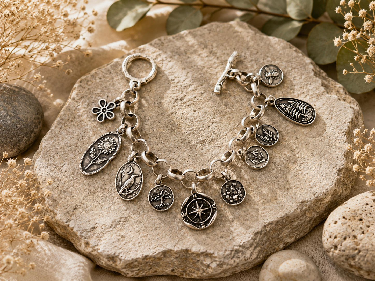 Silver charm bracelet on a stone surface with natural elements Main image