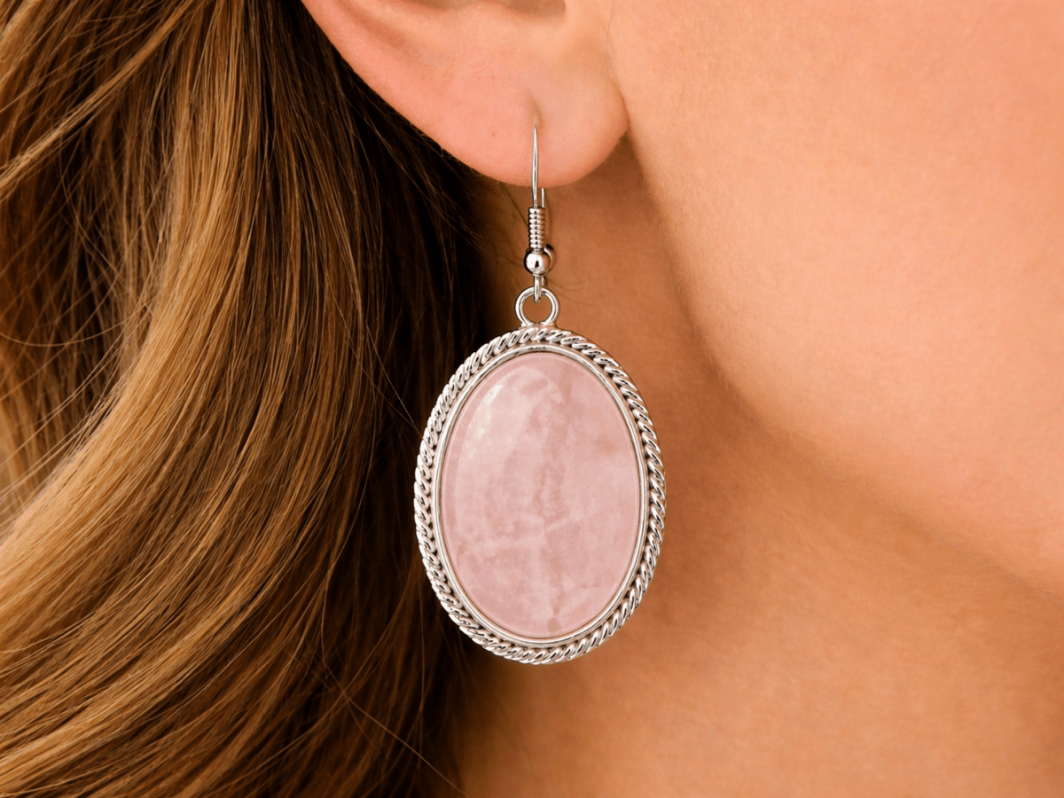Soft, feminine, and effortlessly elegant. These oval drop earrings feature a smooth rose quartz stone set within a twisted silver frame, creating a delicate, polished finish. - Corky & Stoner Main image
