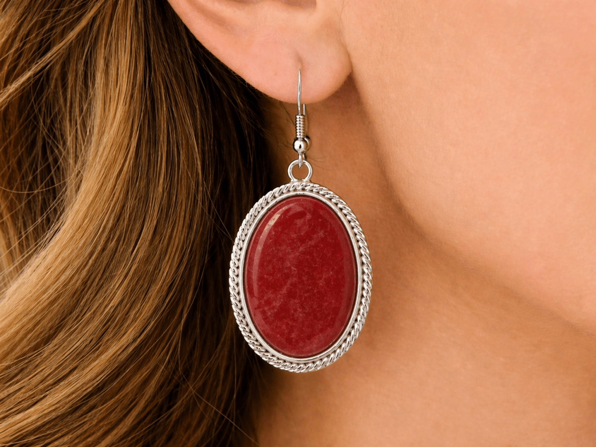 Warm, vibrant, and full of energy. These oval drop earrings feature a smooth red jade stone set within a twisted silver-tone frame, creating a rich, eye-catching finish - Corky & Stoner Main image