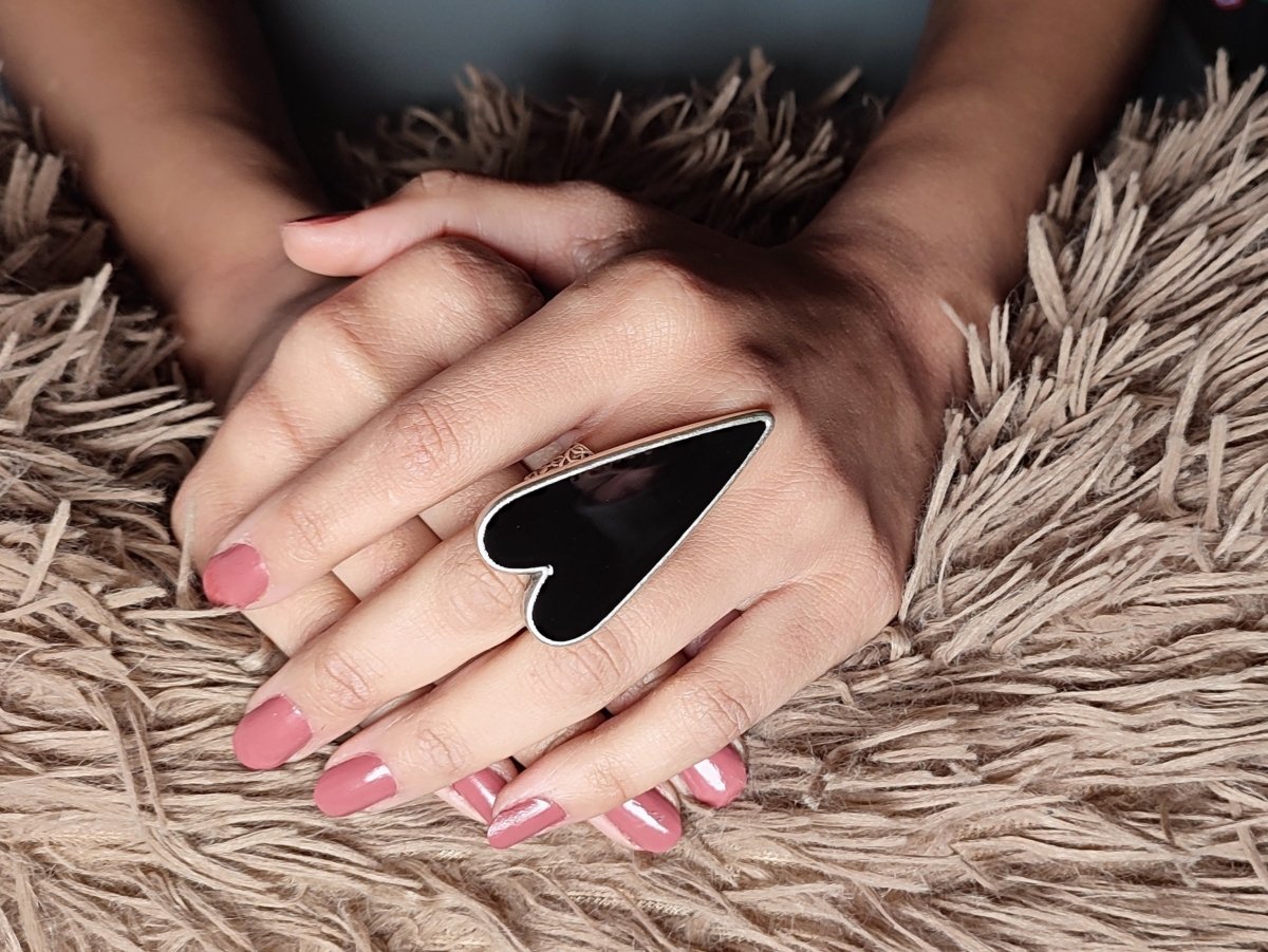 A models hand wearing a large black heart shaped ring