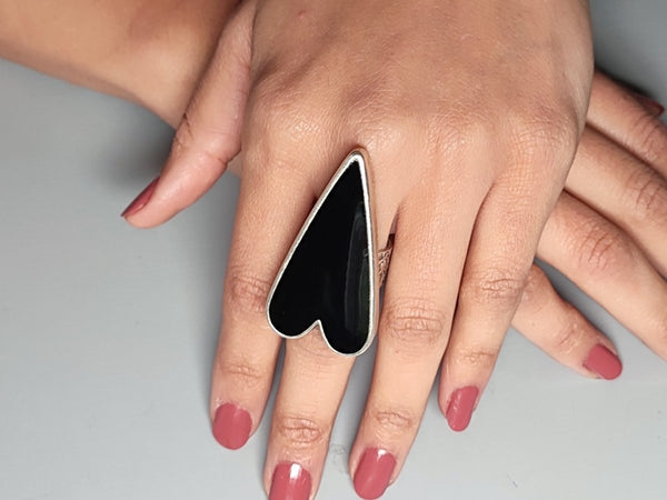 A models hand wearing a large black heart shaped ring