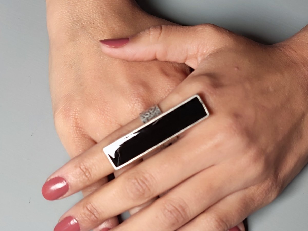 A models hand wearing a long slim black ring