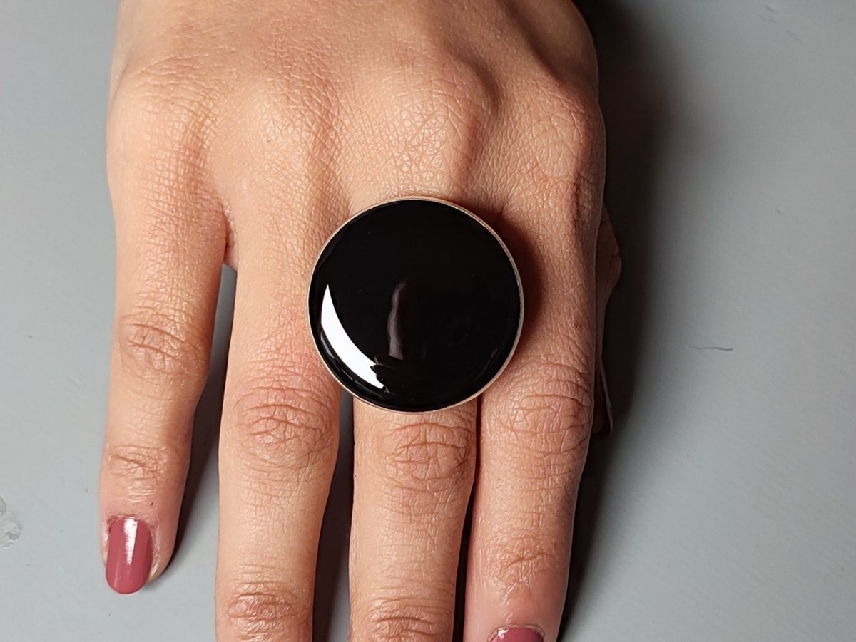 A models hand wearing a round black ring
