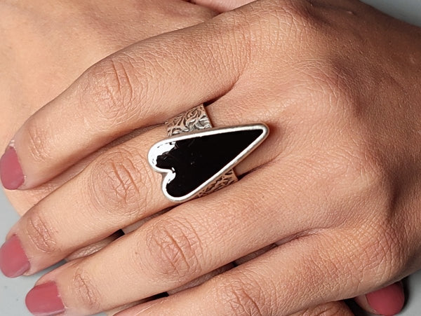 A models hands wearing a black heart ring