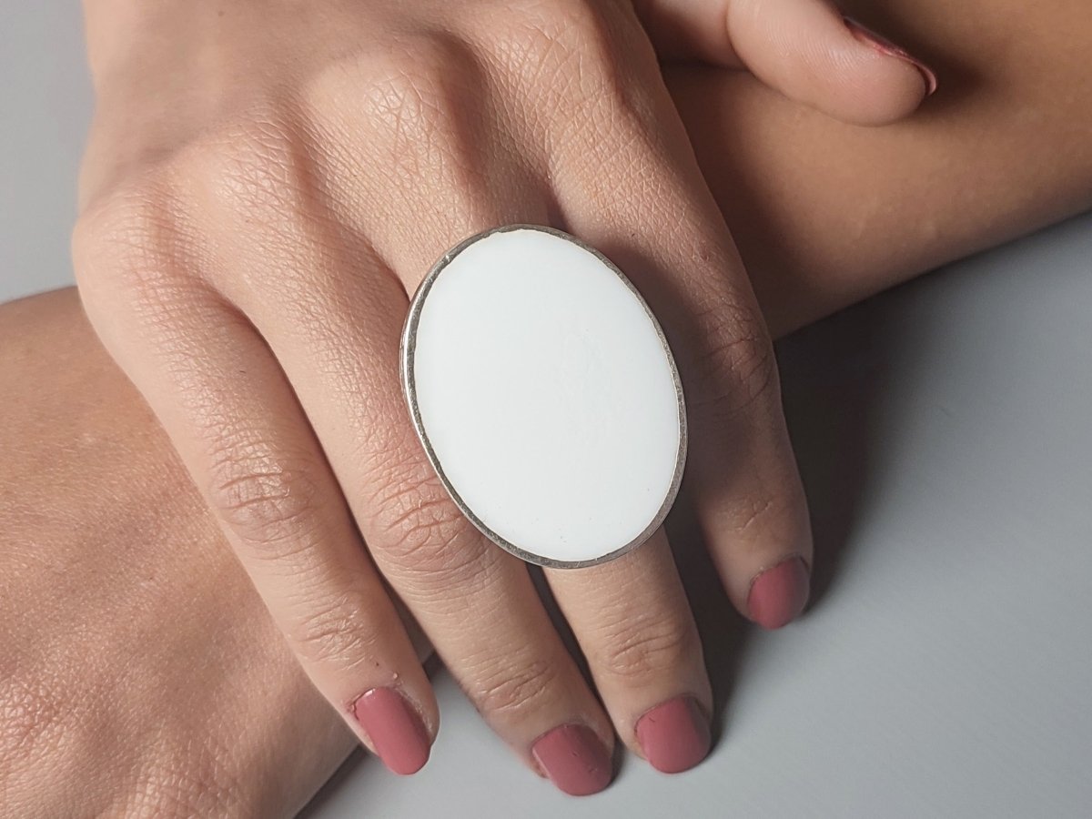 A models hand wearing a white oval ring