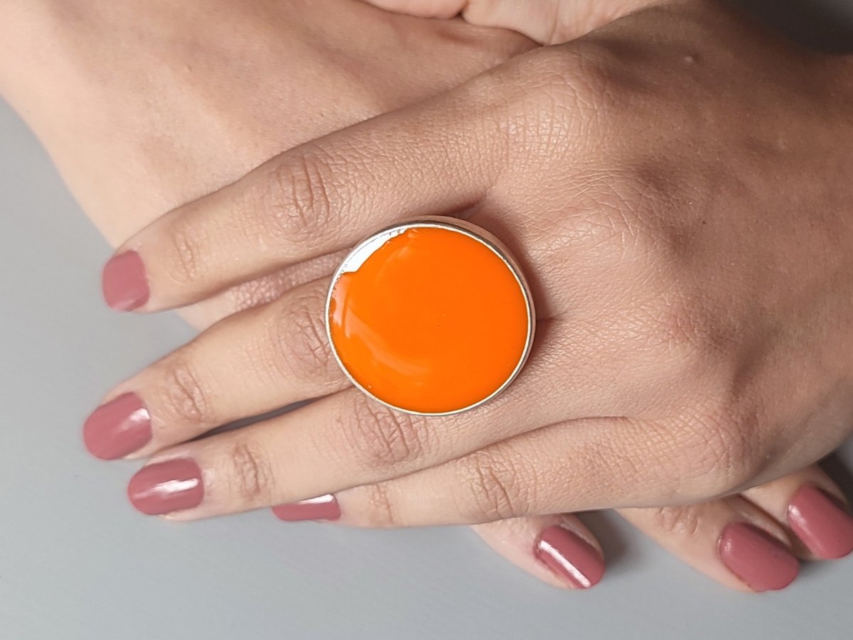 A models hand wearing a round orange ring