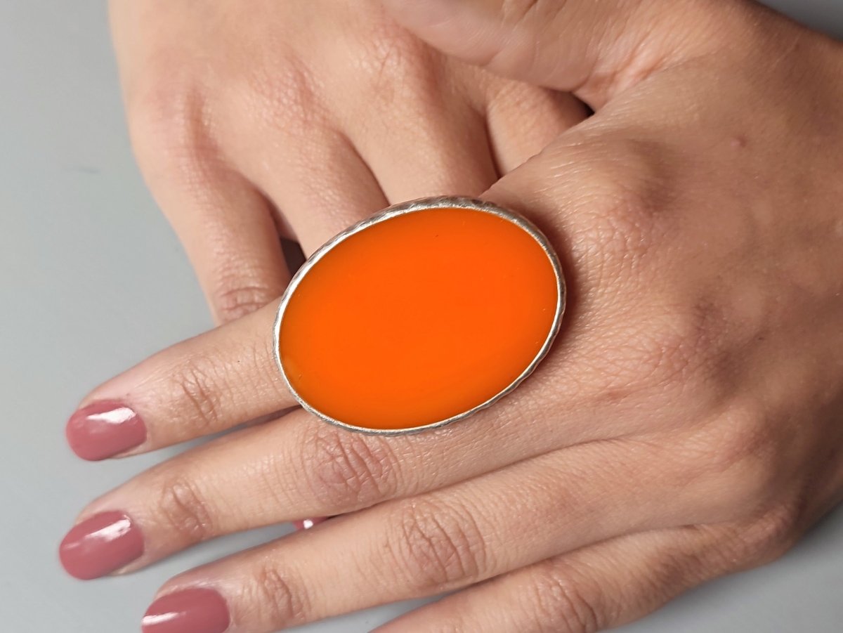 A models hand wearing an orange oval ring