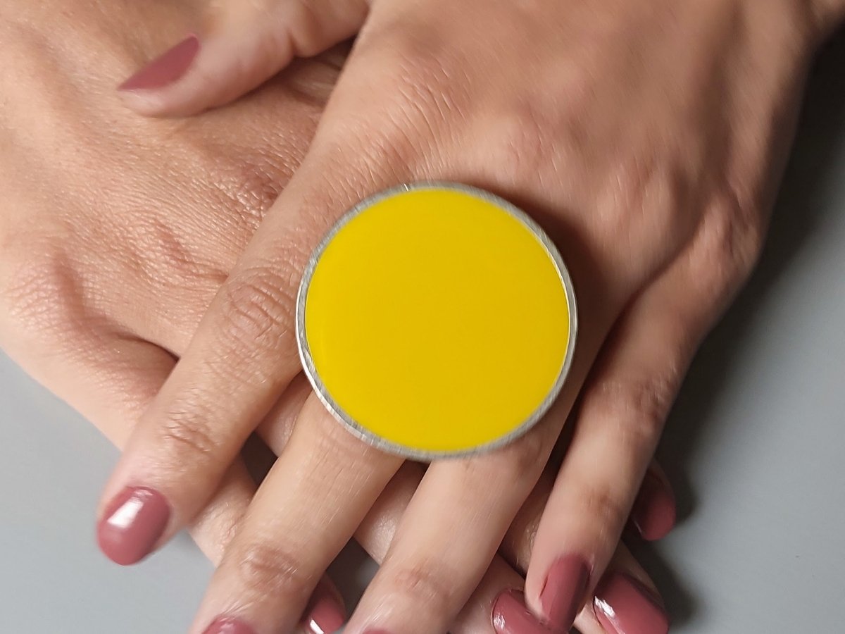 A models hands wearing a  large yellow round ring
