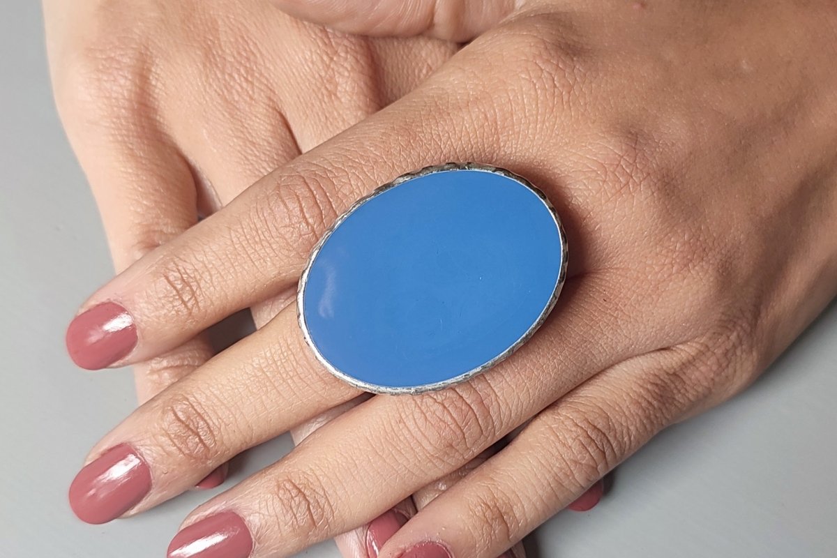 A models hand wearing a blue oval ring