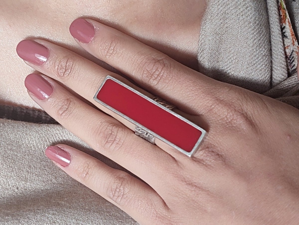 A models hand wearing a long slim dark red ring