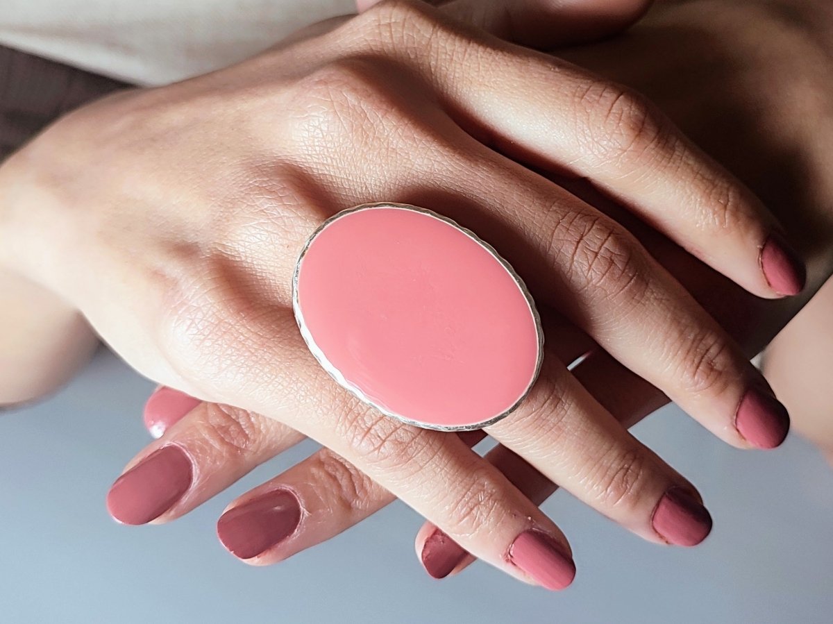 A models hand wearing a salmon pink oval ring