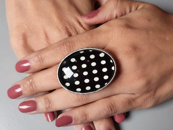 a black and white polka dot ring worn on a models hand