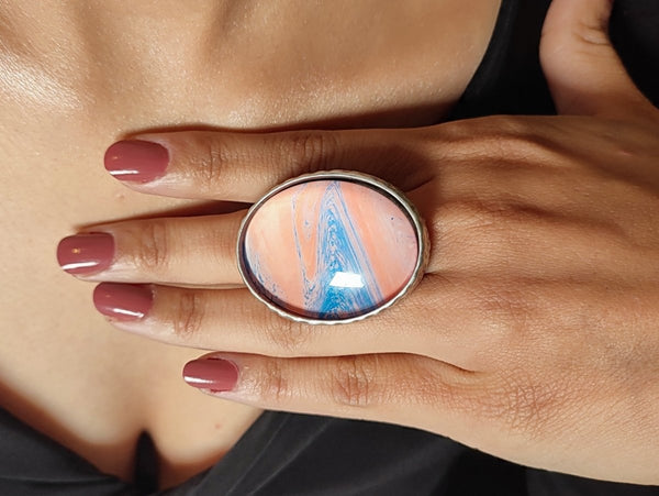 a pink and blue statement ring worn on a models hand