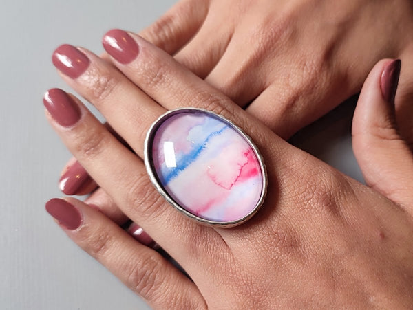 a large pink and blue ring worn on a models hand