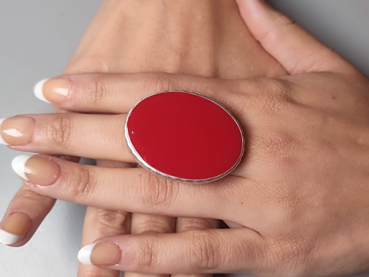 A models hand wearing a dark red oval ring