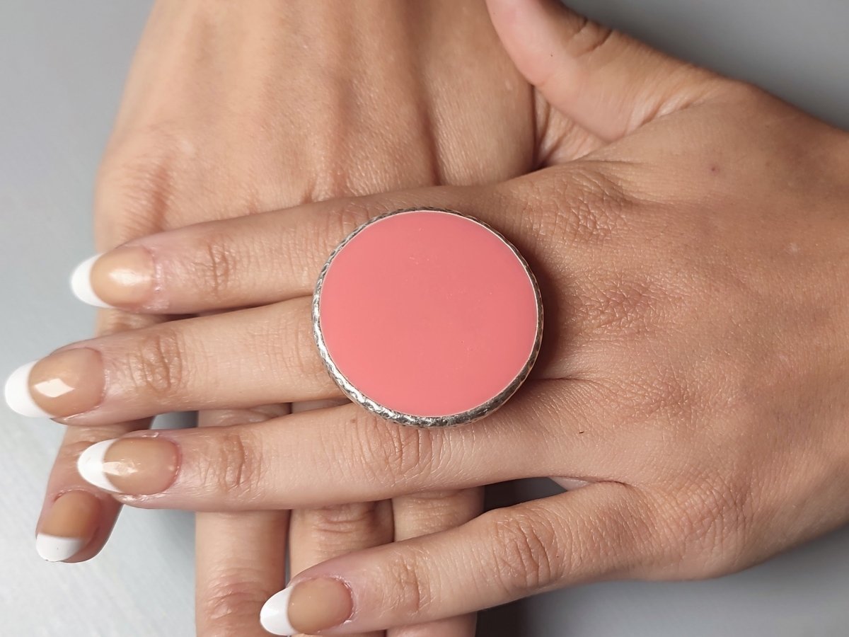 A models hands wearing a large salmon pink ring