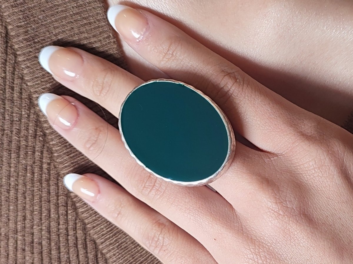 A models hand wearing a dark green ring