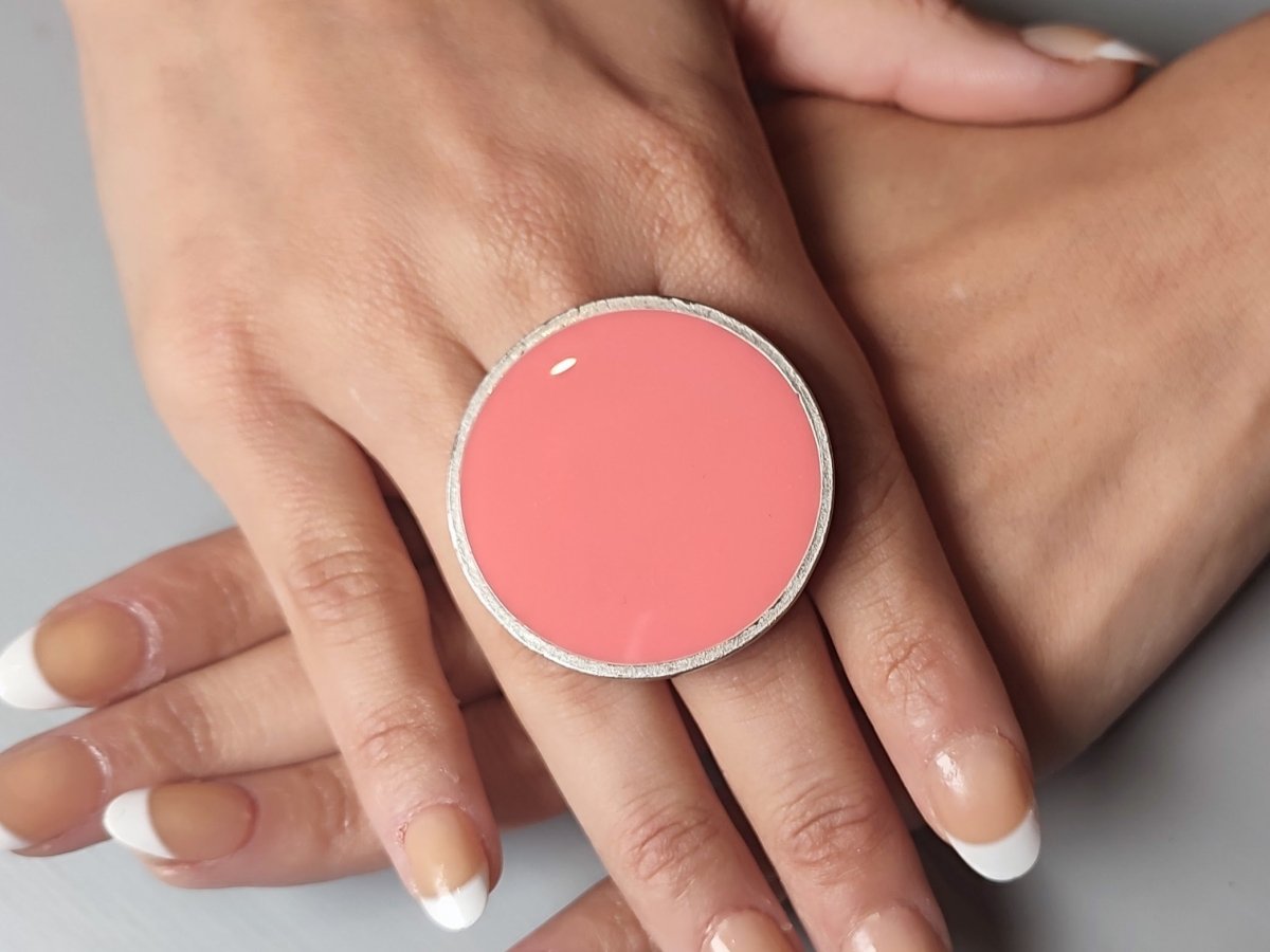 A models hands wearing a salmon pink ring