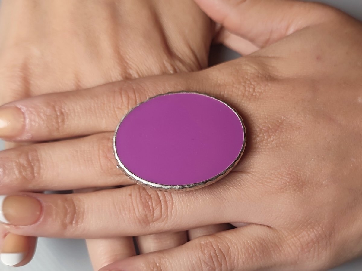 A models hand wearing a violet oval ring