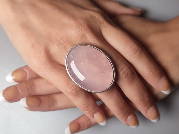 a large rose quartz ring worn on a models hand