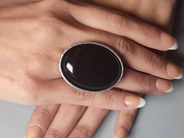 a large black onyx ring worn on a models hand
