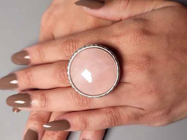 a large rose quartz ring worn on a models hand