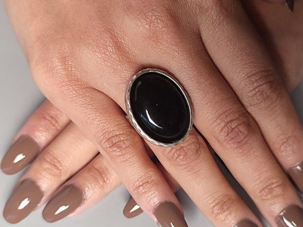 a black onyx oval silver ring worn on a models hand