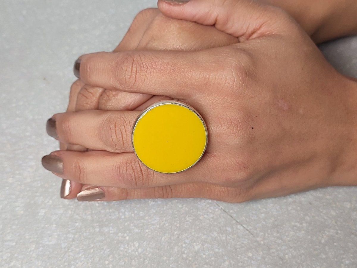 A models hand wearing a round yellow ring