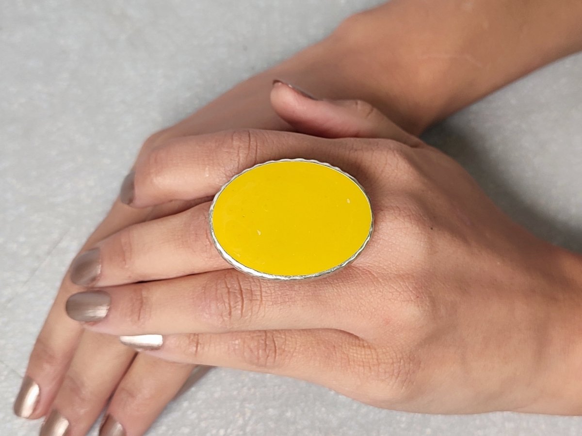 A models hand wearing a yellow oval ring