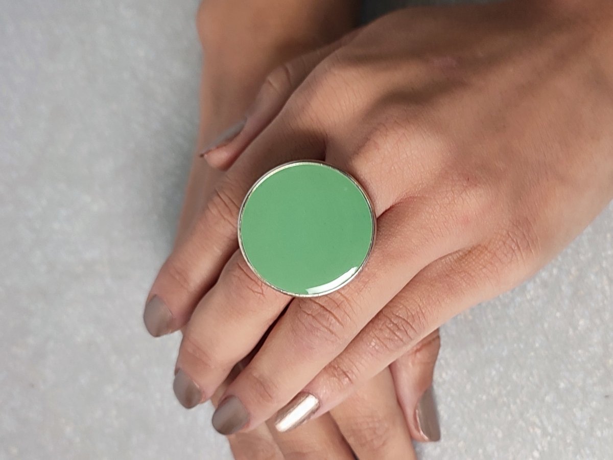 A models hands wearing a large sage green ring