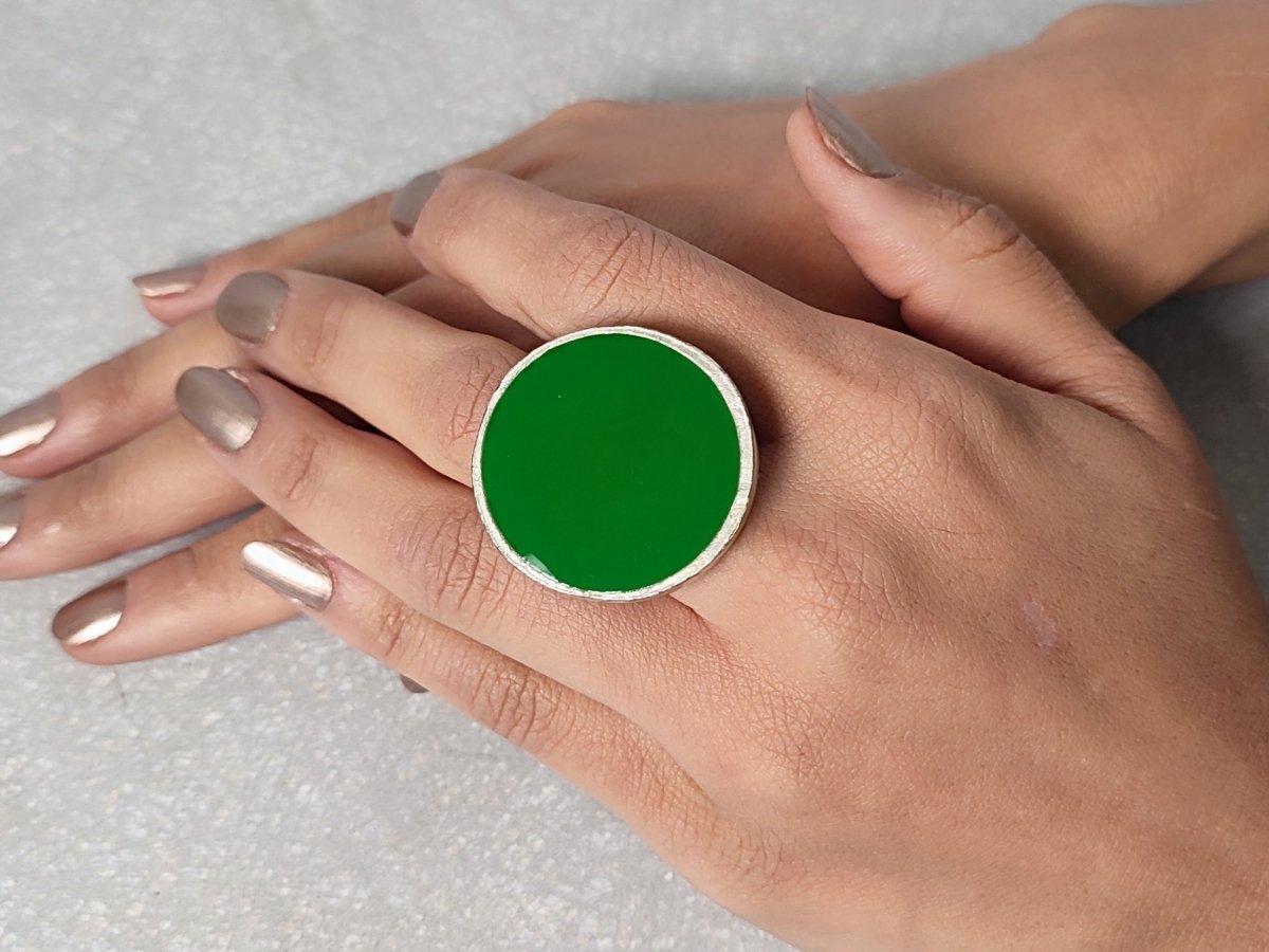 A models hand wearing a round green ring Main image