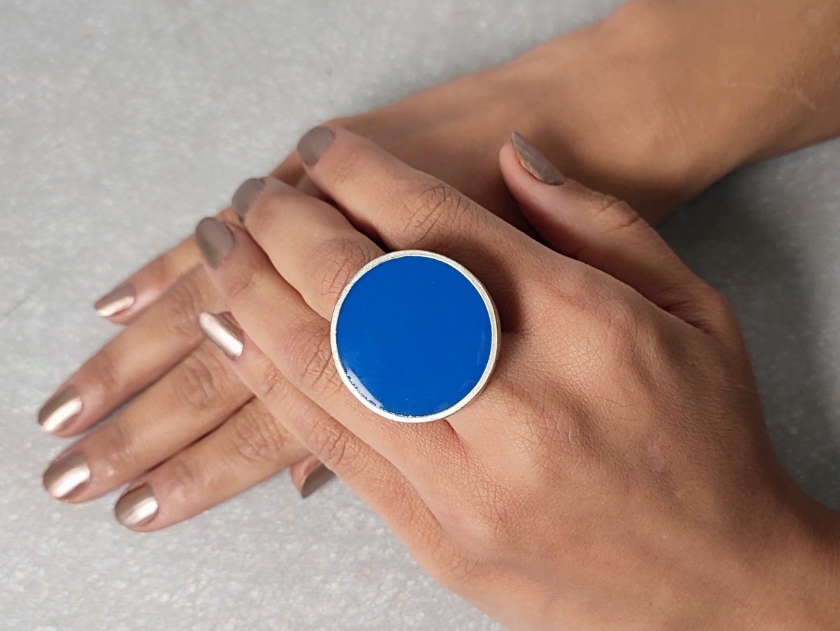 A models hand wearing a round blue ring