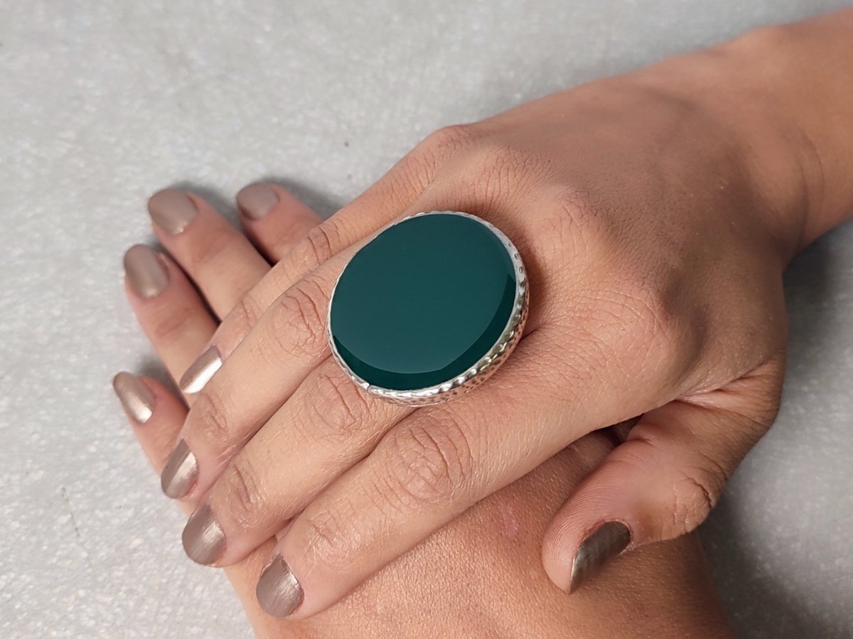 A models hands wearing a large dark green ring