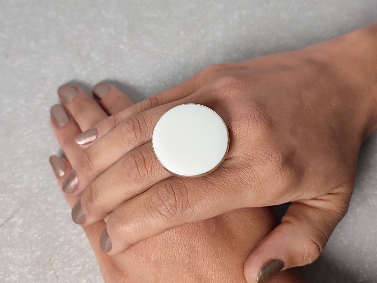 A models hand wearing a round white ring