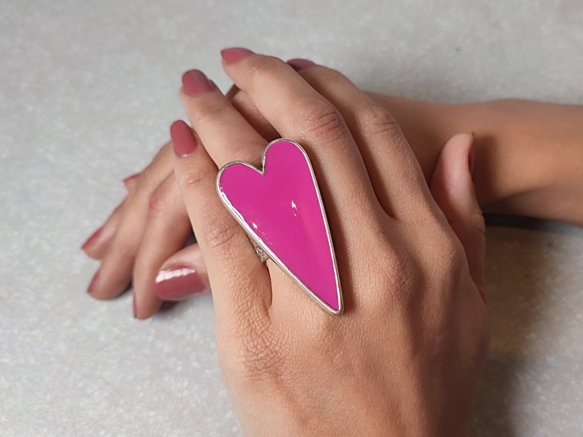 A models hand wearing a large bright pink heart shaped ring