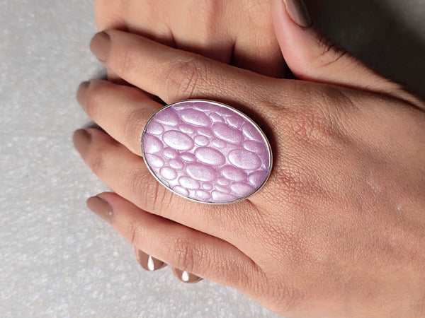 a lilac ring with a textured surface worn on a models hand