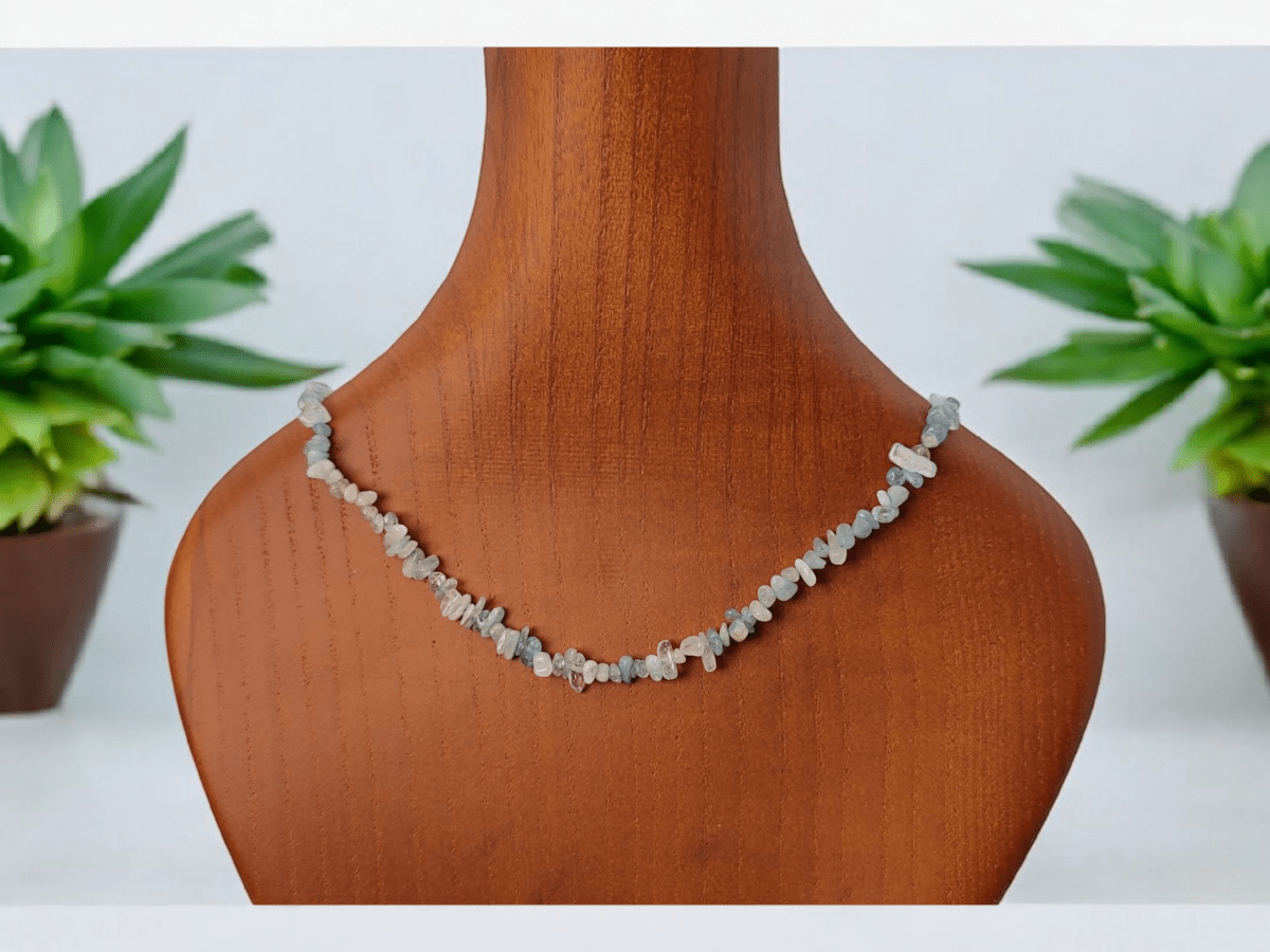 A slim Aquamarine hand beaded choker on a wooden bust