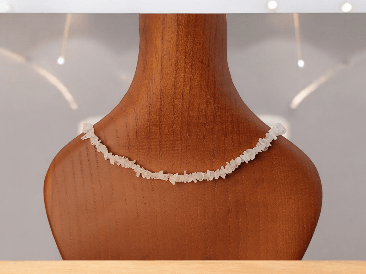 A white quartz beaded choker on a wooden bust