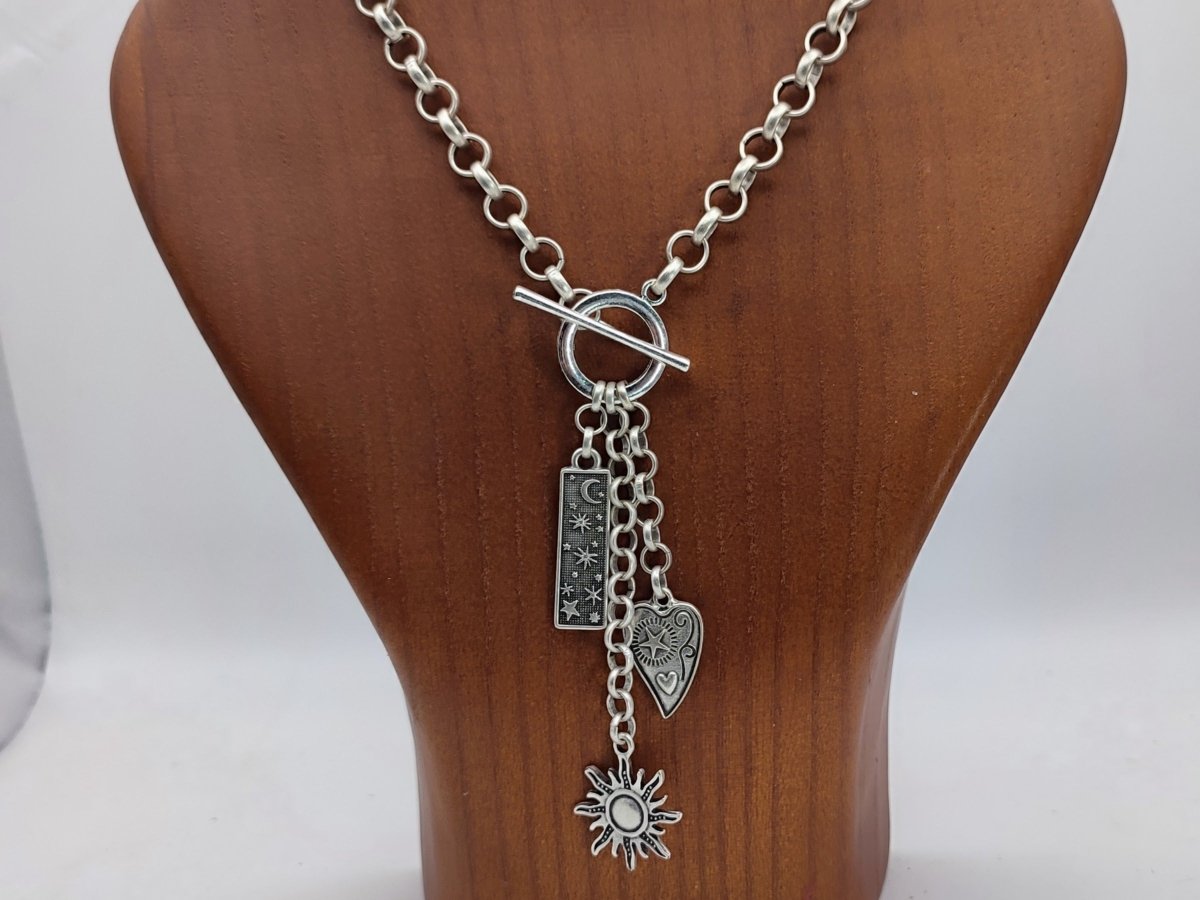 Celestial Charm Lariat Necklace with stars and moon charms on a wooden bust 