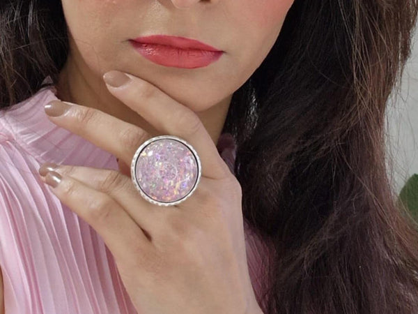 a model with brown hair and a pink top wearing an opal inspired pin glitter ring